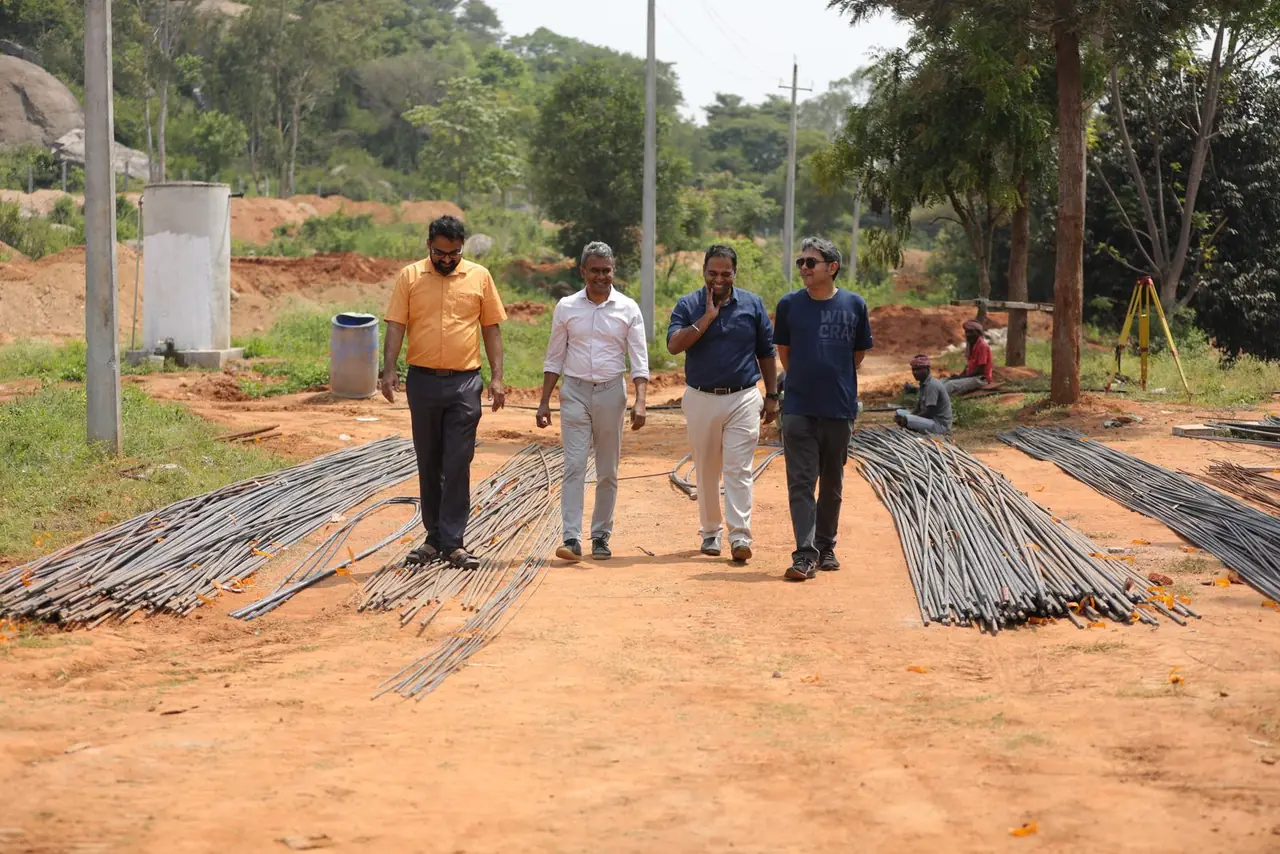 The team walking past bundles of rebar on the site road