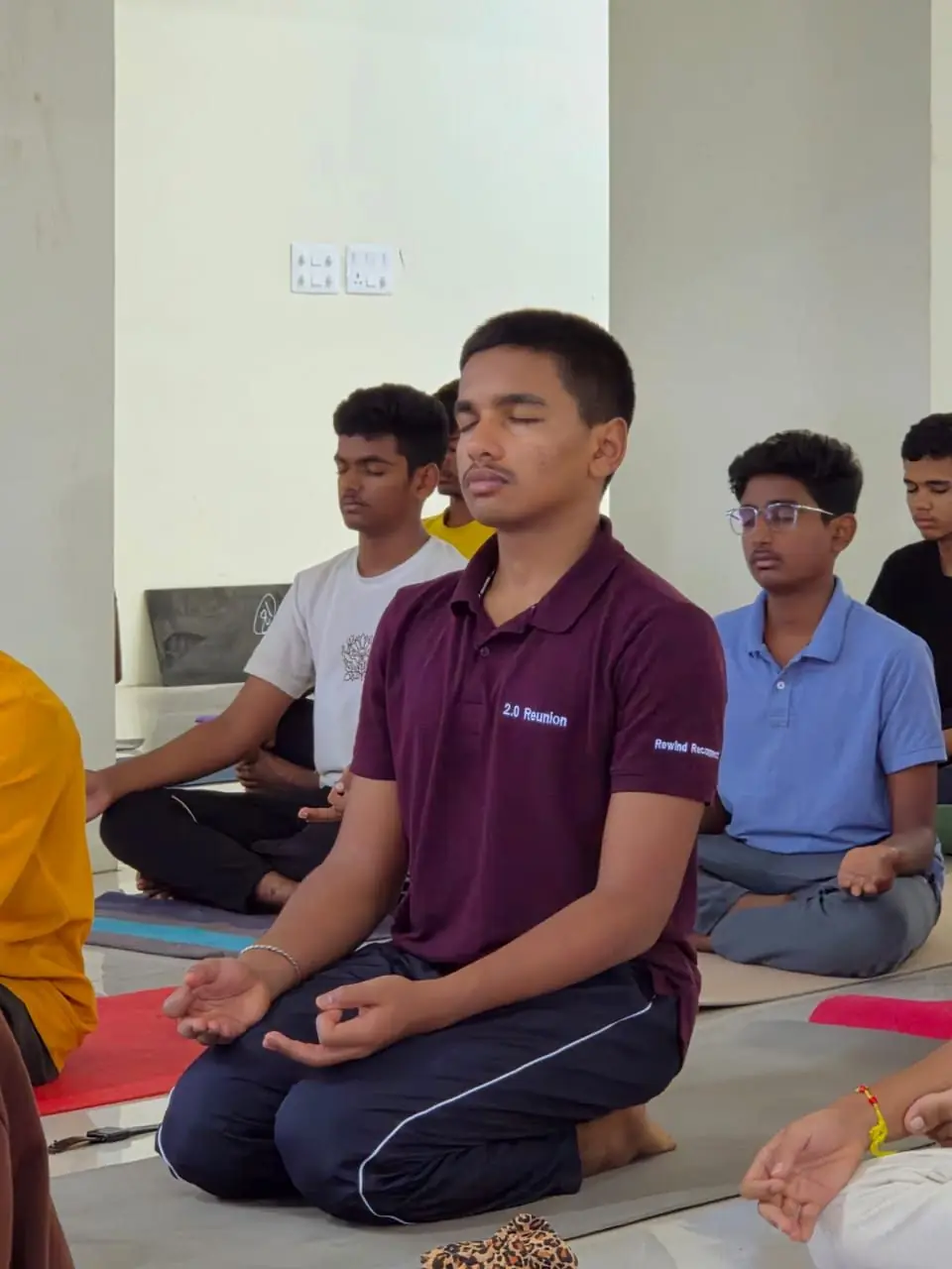 A student practising slow breathing with eyes closed during morning yoga