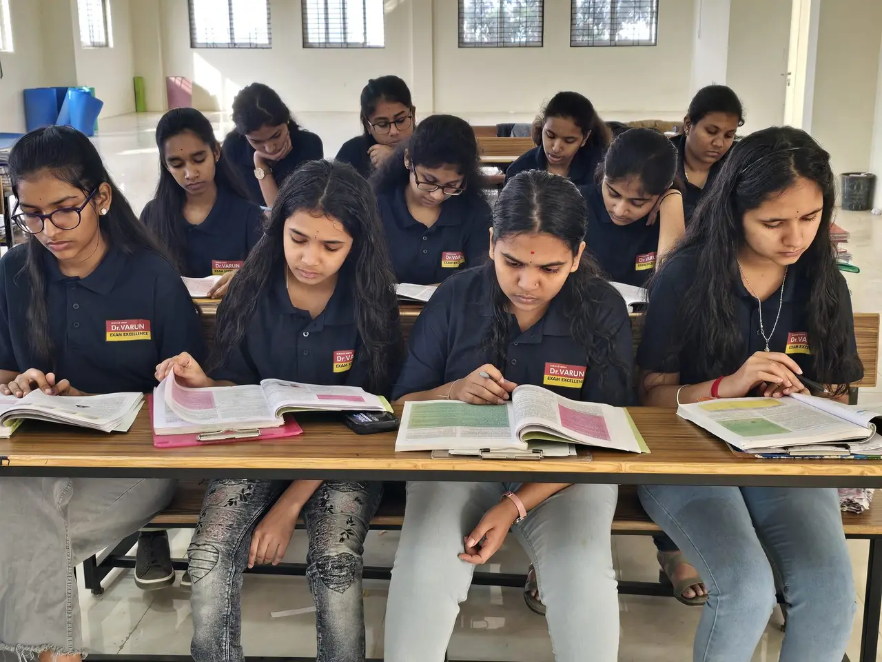 Girl students studying together over open textbooks at a RIMA campus