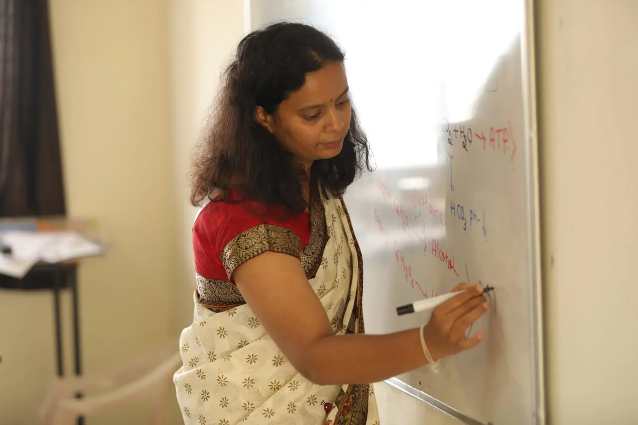 Teacher writing on a whiteboard during an integrated PUC science class