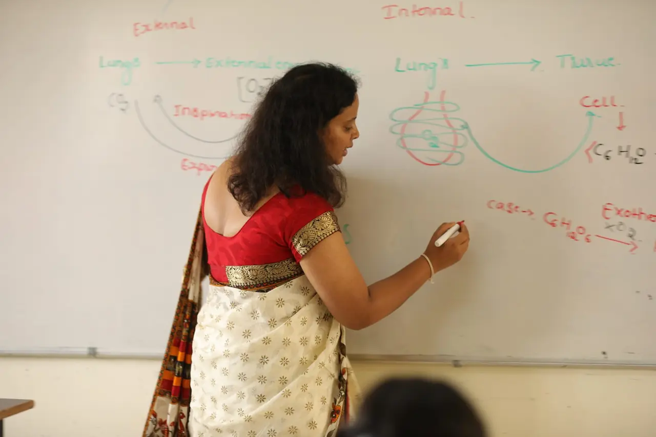 Biology teacher drawing the respiration pathway on a whiteboard in a PUC NEET class