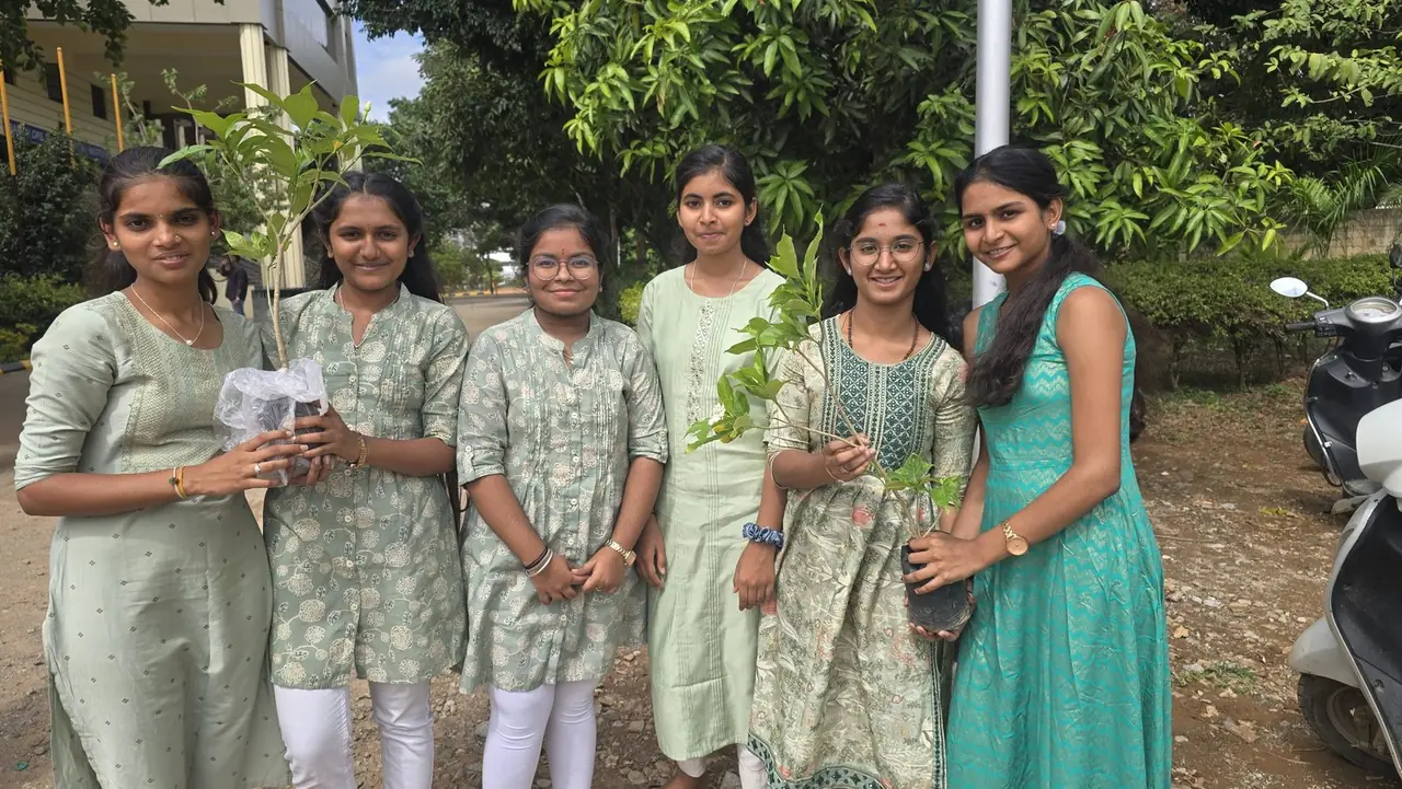 Students holding saplings under mango trees on environment day at a RIMA campus